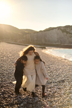 Happy mom with her two children on a rocky beach