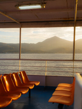 Plastic chairs on deck of a ferry lit by sunlight 