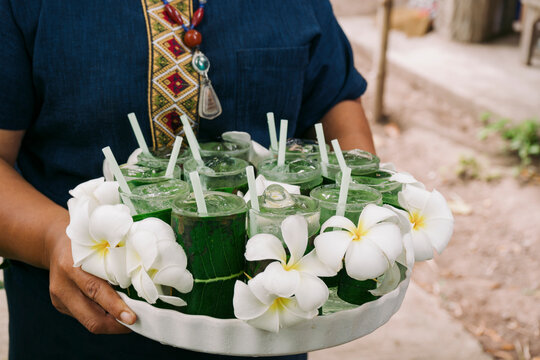 Waitress serving pandanus juice on a tray decorated with flowers