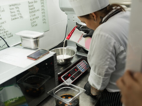 Cook pouring milk in bowl on scales 