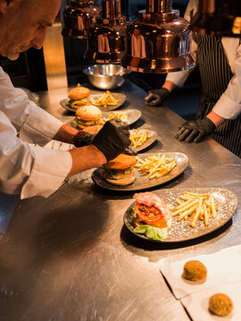 Chefs Preparing Gourmet Burgers and Fries in a Busy Kitchen
