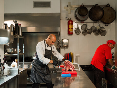 Chef using saw to cut meat 