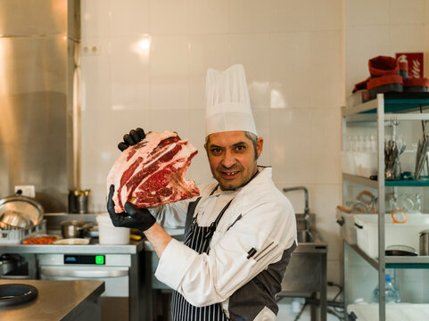 Chef Showing off a Large Cut of Meat in a Kitchen