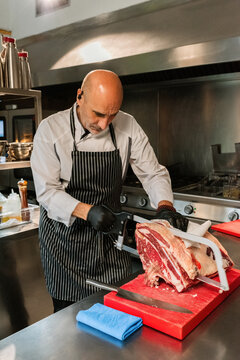 Chef Skillfully Butchering Meat in a Modern Kitchen Setting