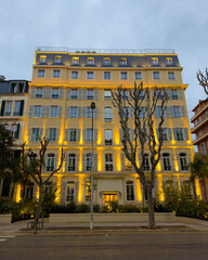 Obraz premium Beautiful yellow historic building in Nice, facade illuminated at night, European architecture.
