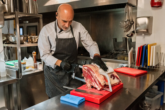 Chef Skillfully Butchering Meat in a Commercial Kitchen