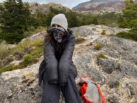 traveler resting on rocky mountain terrain in cold weather, ugc