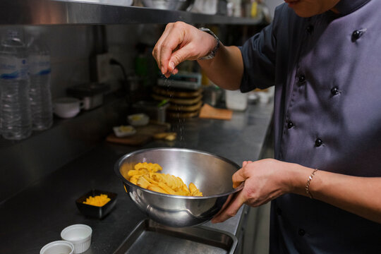 Chef cooking potato fries inside a kitchen