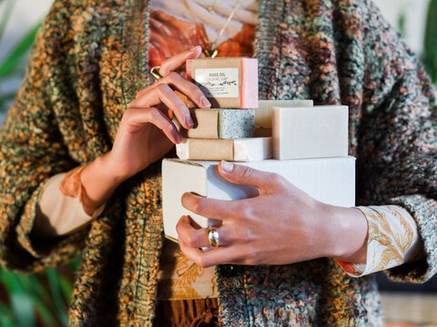 Woman Holding Assorted Handmade Soaps in a Cozy Setting