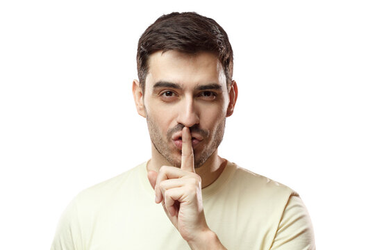 Close up shot of handsome tricky man with shh gesture, asking for silence or to be quiet, isolated on pink background