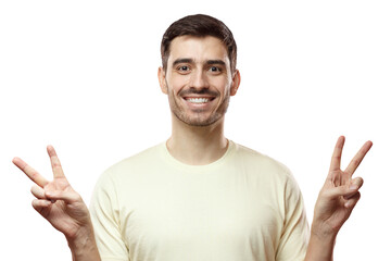 Fototapeta premium Closeup photo of young positive European man in beige T-shirt isolated on pink background feeling peaceful and comfortable, smiling and showing V sign with fingers, enjoying relaxed atmosphere