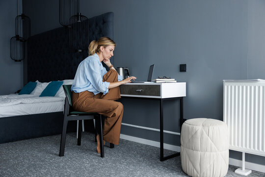 Side view of businesswoman using and watching laptop on nightstand