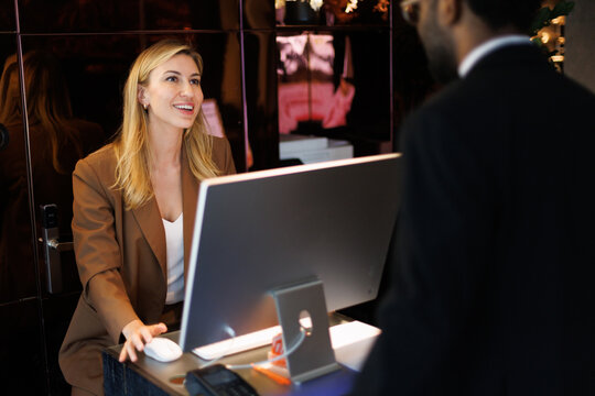 Adult smiling female receptionist looking at partial black businessman