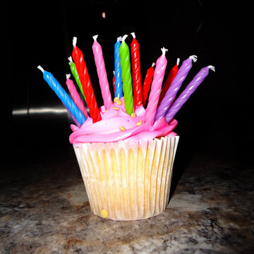A Brightly Colored Cupcake with Many Candles
