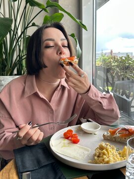 A young woman with a bob haircut enjoys her breakfast, ugc