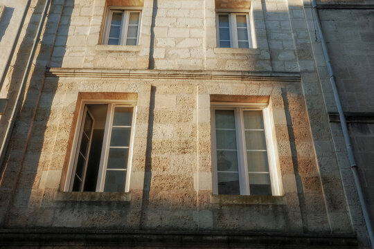 Sunlight Reflects on Textured Stone Wall With Several Windows