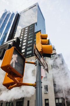 Traffic light and one-way sign in city street with steam