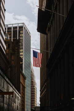 American flag hanging between tall city buildings