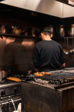 Chef Cooking Meat on Grill in Busy Kitchen at Night