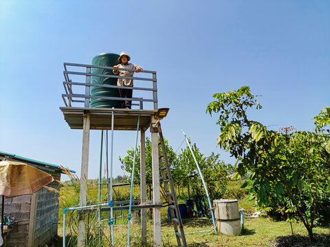 Elderly Southeast Asian woman on a water tank inside a farm