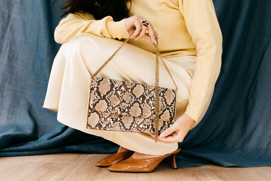 Anonymous woman holding stylish snakeskin clutch bag