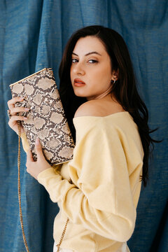 Woman holding snakeskin pattern clutch 