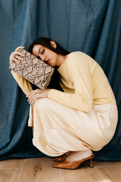 Woman crouching with snakeskin purse