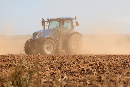 Tractor Raising Dust in Plowed Field