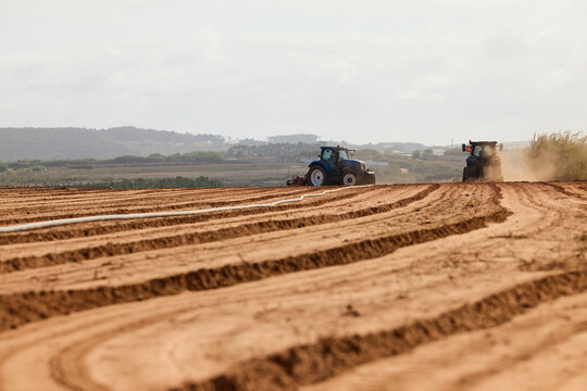 Tractors Tilling Rows in Sandy Farmland