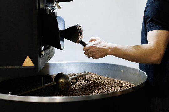 Worker controlling process of coffee roasting on roaster machine