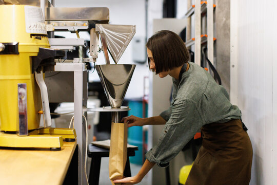 Female worker controlling how coffee beans falling out in package