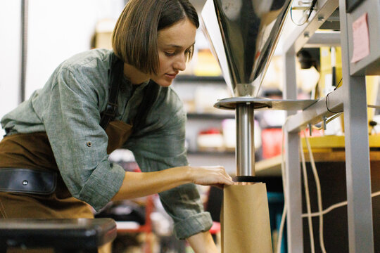 Female worker controlling how coffee beans falling out in package
