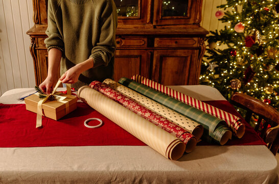 Gift Wrapping with Holiday Paper Rolls and Ribbon at Festive Table