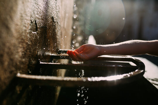 Hand reaching for water from stone wall