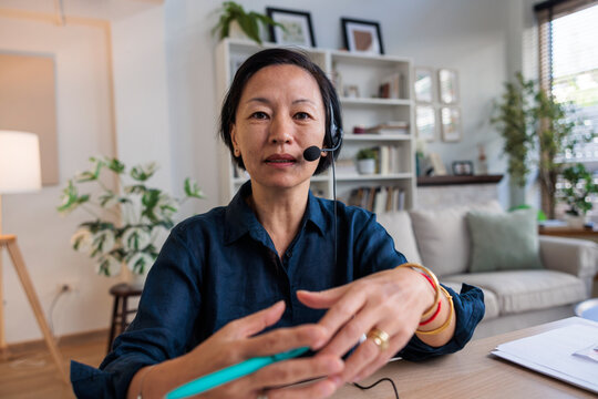 Woman with headset on video call in home office.