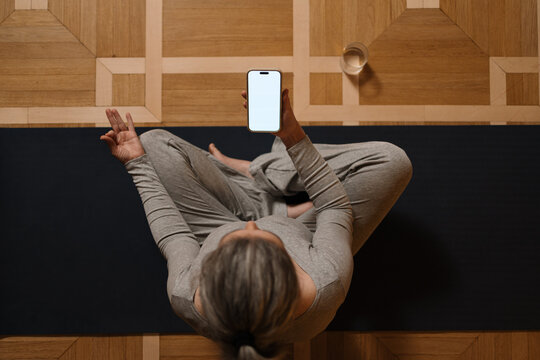 A woman uses a white screen mobile phone while exercising