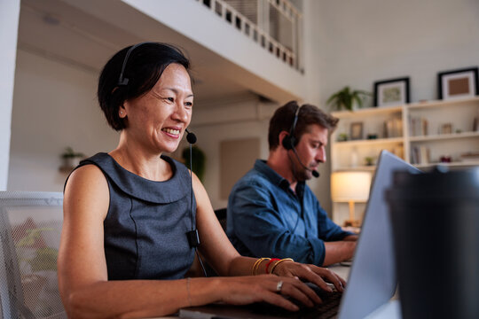 Two people working from home with headsets and laptops.