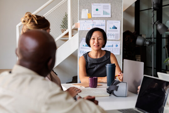 Diverse team meeting with charts, laptops, and VR headset.