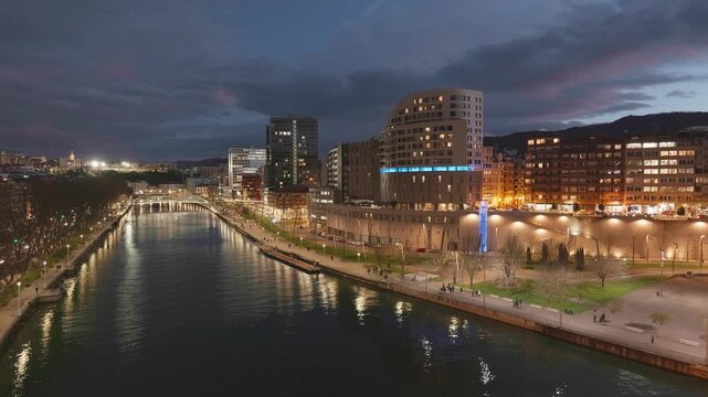 Night video from La Salve Bridge in Bilbao Spain showing the Nervion River promenade and modern and historic buildings.