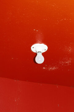 A single ceiling light bulb on a red room