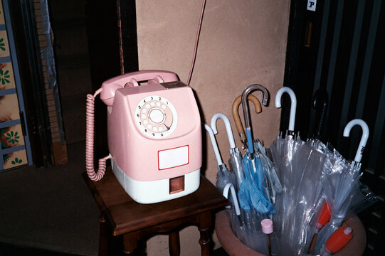 Pink vIntage dial up phone next to umbrellas