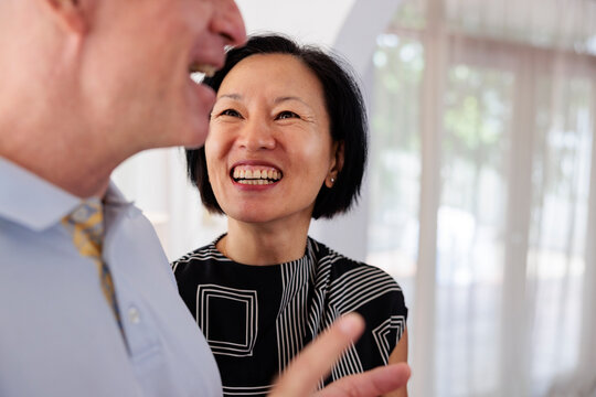 Woman smiles at man, both laughing indoors.
