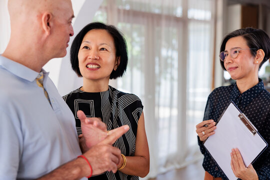 Three people in conversation, one holding a clipboard.