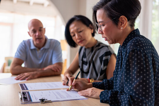 Couple signs real estate purchase agreement with agent.