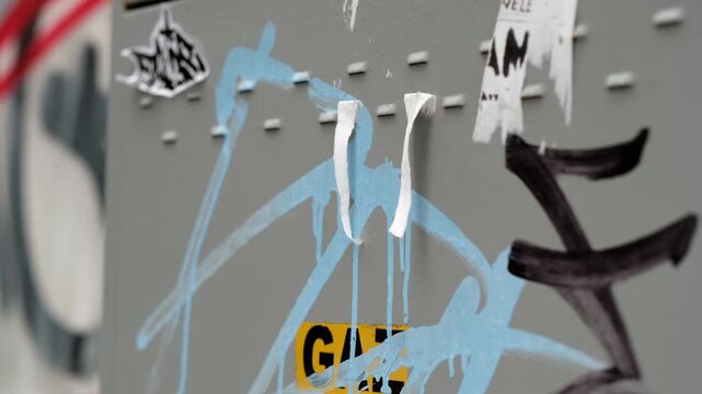 Three-quarter perspective of an old gas meter with colorful graffiti and shredded advertisements