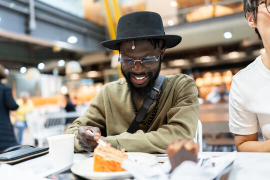 Smiling man enjoying a sweet dessert and coffee at a cafe