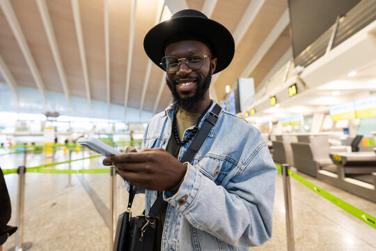 Happy man traveling, smiling and checking details on phone at airport