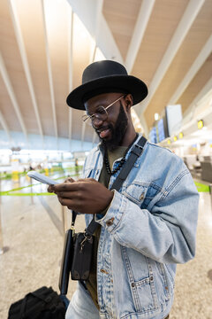 Smiling man checking phone at airport terminal