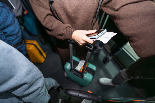 Passenger holding boarding pass and phone at airport bus