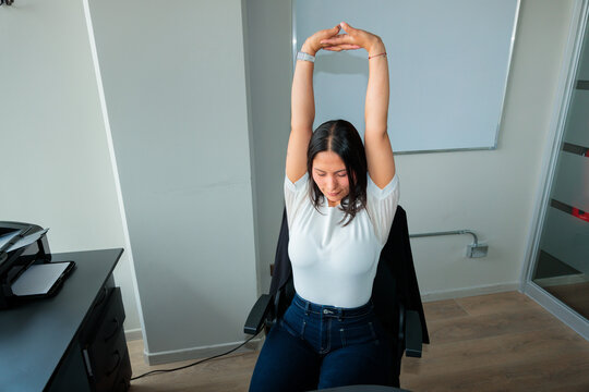 Latina Woman in Office Stretch Break at Desk
